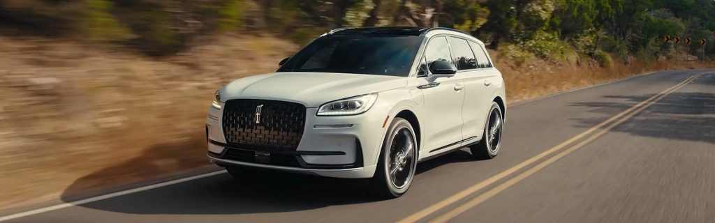 White luxury SUV driving on a scenic highway.