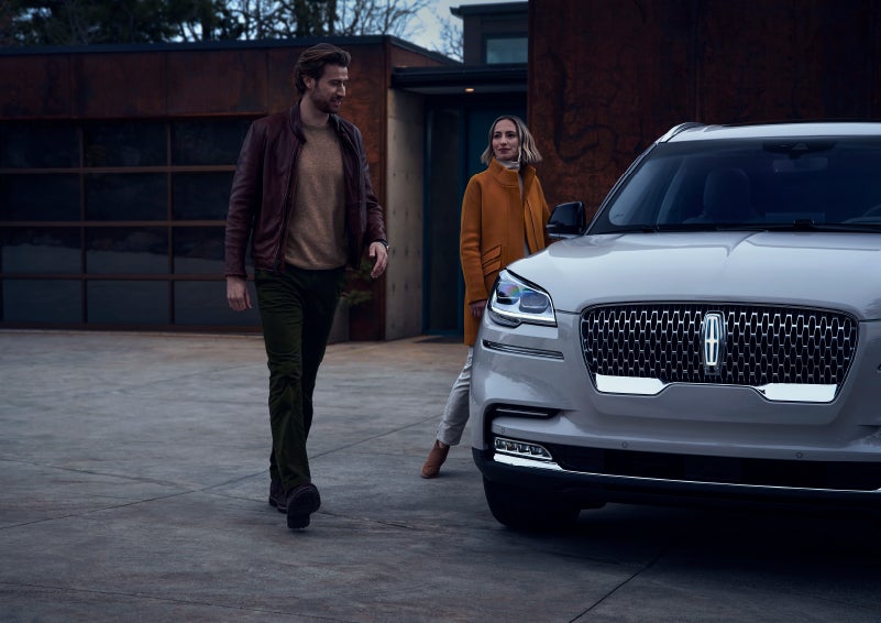 A man and a woman approaching a 2024 Lincoln Aviator® SUV, which illuminates certain lights when they are close | West Point Lincoln of Sugar Land in Houston TX