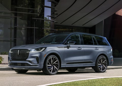 A gray 2025 Lincoln Aviator® SUV is parked outside a modern building showcasing the driver’s side of the vehicle. | West Point Lincoln of Sugar Land in Houston TX