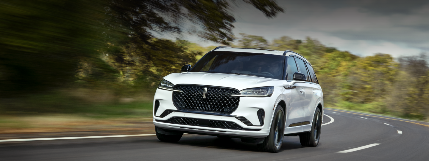 A white 2025 Lincoln Aviator® SUV is being driven down a road lined with trees. | West Point Lincoln of Sugar Land in Houston TX