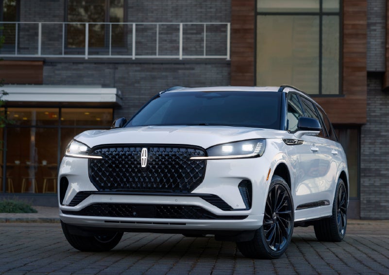 A 2026 Lincoln Aviator® Reserve model is shown with the available Jet Appearance Package parked near a restaurant. | West Point Lincoln of Sugar Land in Houston TX