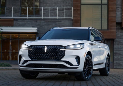 A 2026 Lincoln Aviator® Reserve model is shown with the available Jet Appearance Package parked near a restaurant. | West Point Lincoln of Sugar Land in Houston TX
