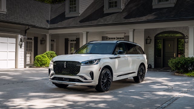 A white 2026 Lincoln Aviator® SUV is parked in the driveway of a luxury home. | West Point Lincoln of Sugar Land in Houston TX