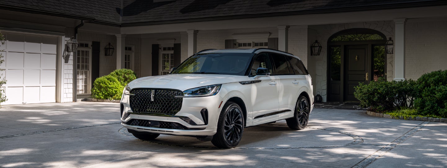 A white 2026 Lincoln Aviator® SUV is parked in the driveway of a luxury home. | West Point Lincoln of Sugar Land in Houston TX