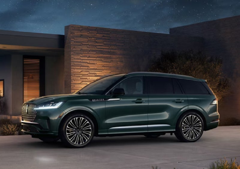 A green 2027 Lincoln Aviator® SUV is parked outside a contemporary home. | West Point Lincoln of Sugar Land in Houston TX