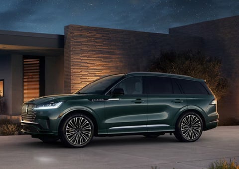 A green 2027 Lincoln Aviator® SUV is parked outside a contemporary home. | West Point Lincoln of Sugar Land in Houston TX