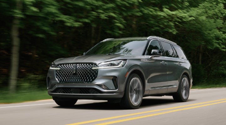 A 2027 Lincoln Aviator® SUV is being driven down a road lined with trees. | West Point Lincoln of Sugar Land in Houston TX