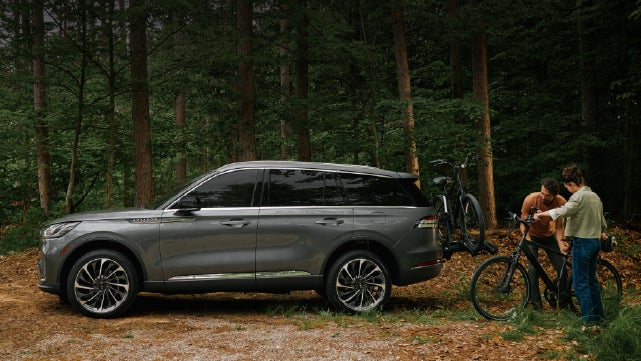 A father and son load e-bikes on a bike rack attached to a 2027 Lincoln Aviator® SUV. | West Point Lincoln of Sugar Land in Houston TX